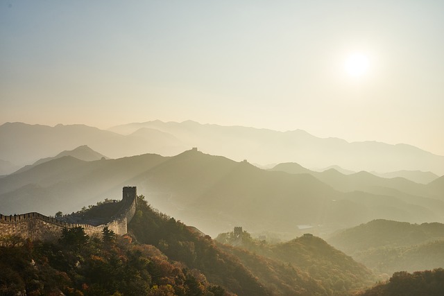 1. An aerial view capturing the vast expanse of the Great Wall of China snaking across rugged terrain, watchtowers and human figures dotted along its path under clear skies.